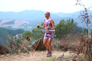 trail running woman wearing violet trail alchemy print outfit in front of sweeping mountain views